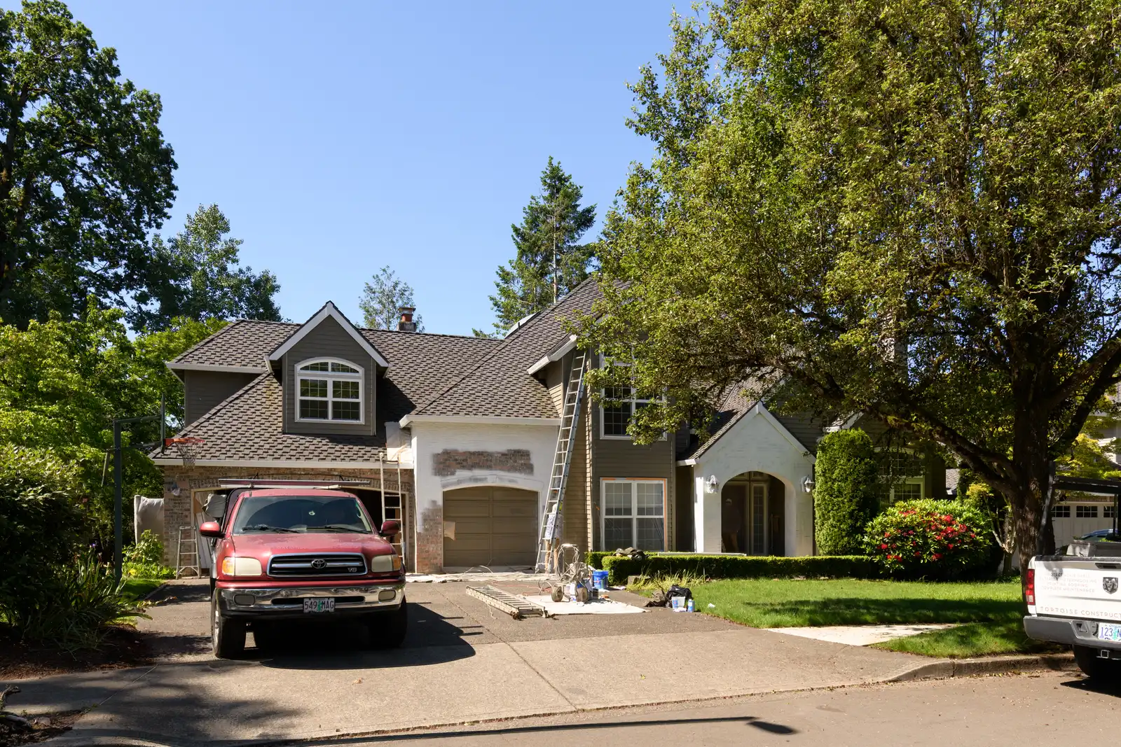Lake Oswego home before construction begins, with work trucks parked out front