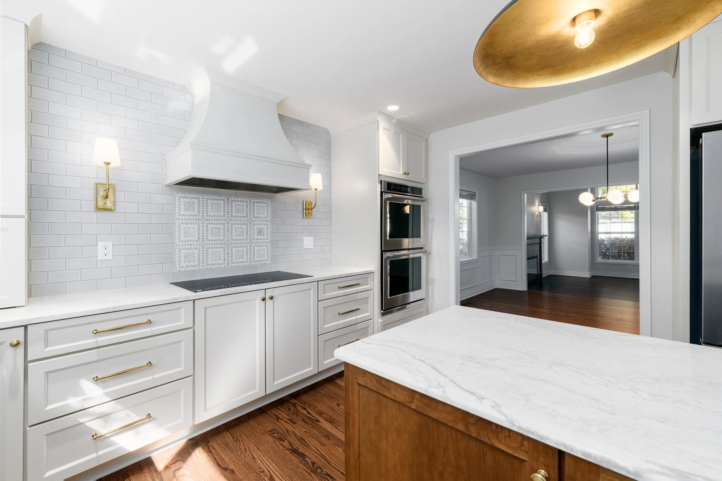 Remodeled Lake Oswego kitchen with white cabinetry, paneled range hood, and double wall ovens